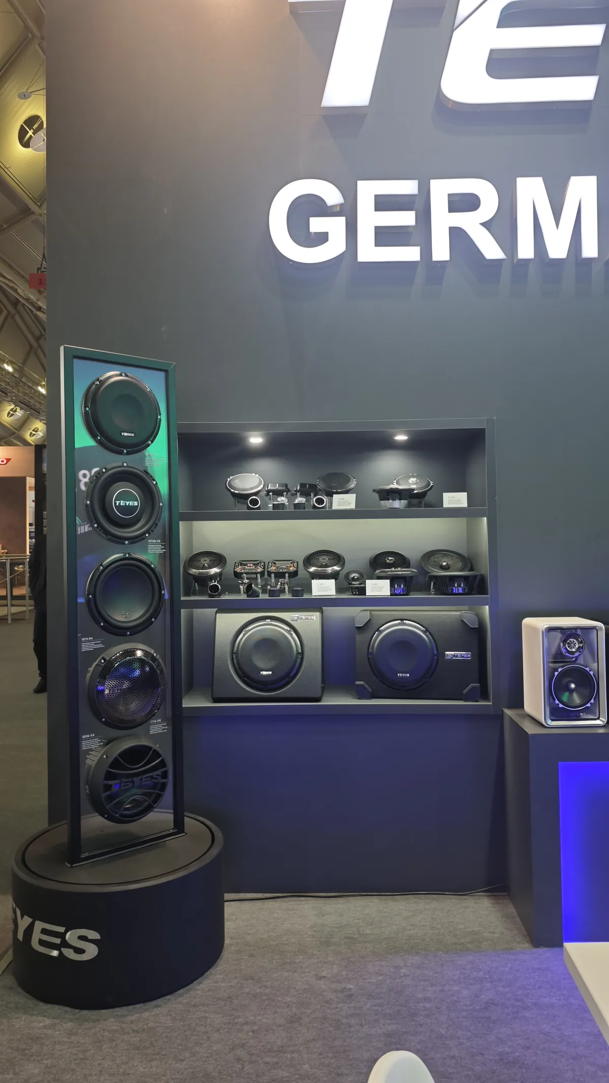 Panorama of the TEYES car audio showcase at Automechanika Frankfurt 2026 — rotating subwoofer tower, speaker and amplifier shelves, and the demo speaker