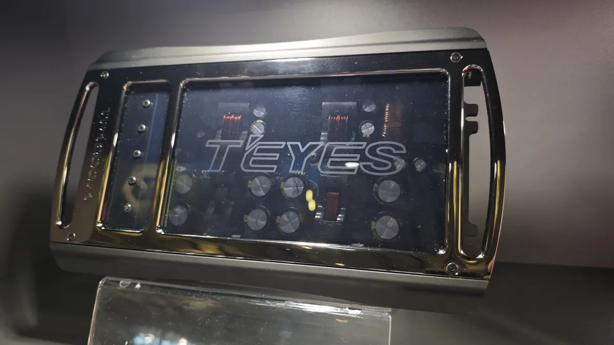 Inside a TEYES TD series amplifier — exposed PCB with output coils and capacitors visible through the clear cover
